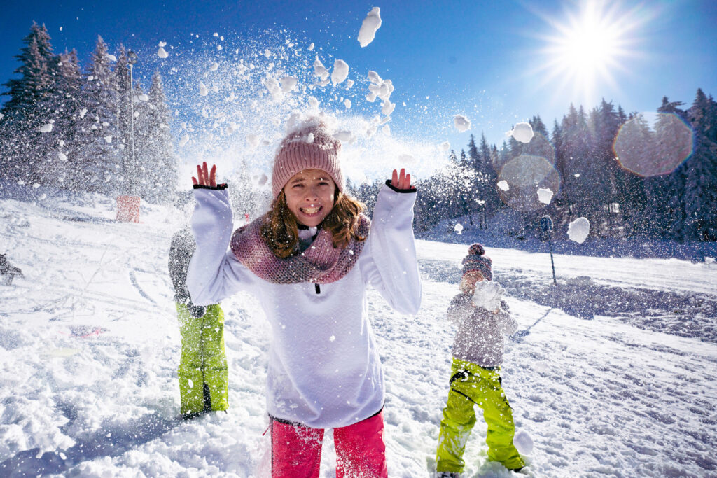 Teenage girl making a face while her brothers throw snow at her