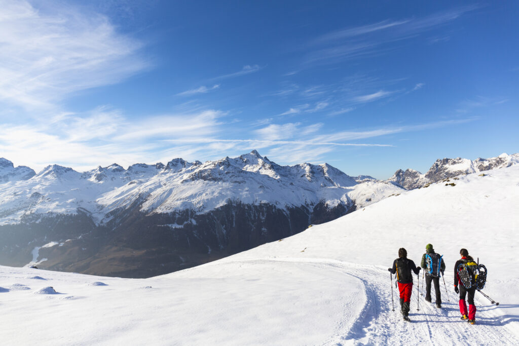 Hikers walking on snow covered road in high mountain