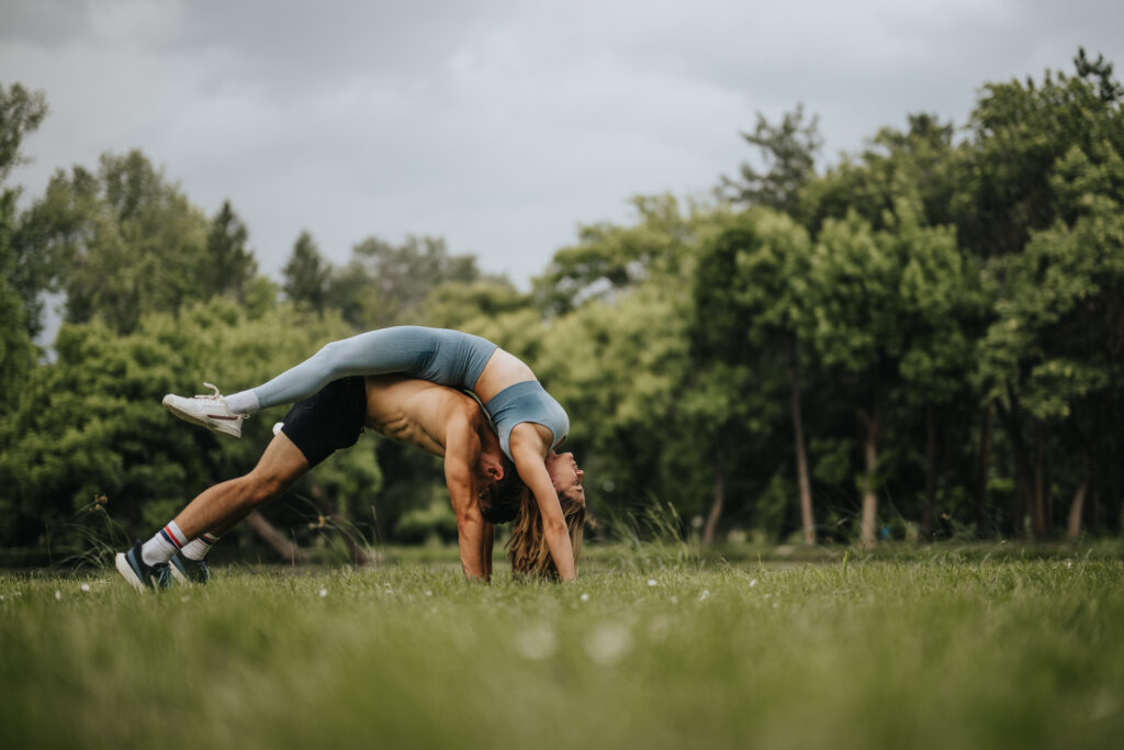 Couple performing acro yoga outdoors in a green park