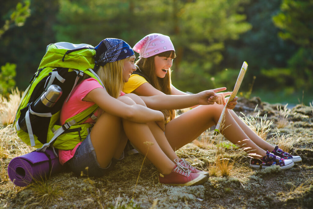 Girls with backpack Looing at map. Adventure, travel, tourism concept
